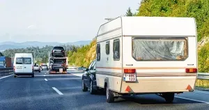 auto met caravan rijdt op een drukke autosnelweg richting vakantie