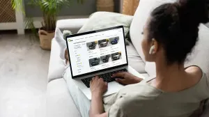 vrouw zit op een sofa en kijkt op een laptop naar het online aanbod bij VAB-Tweedehandswagens