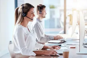 2 helpdesk-medewerkers met headsets werken aan hun computer