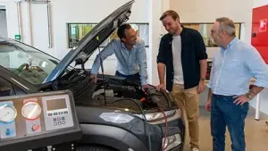 3 mannen staan te praten aan een open motorklep met diagnostische apparatuur ernaast