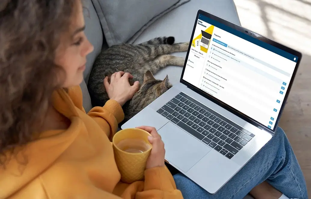 een meisje volgt een online theorieopleiding van VAB-Rijschool terwijl ze haar kat aait