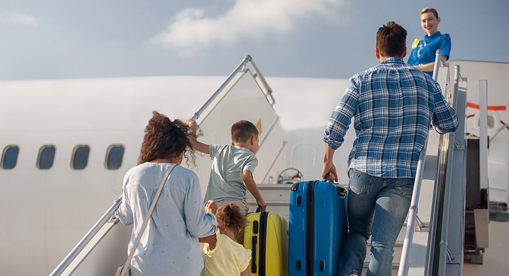 vader en moeder met 2 kinderen gaan de trap van een vliegtuig op om in te stappen