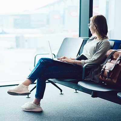 vrouw kijkt uit het raam van een terminal in een luchthaven