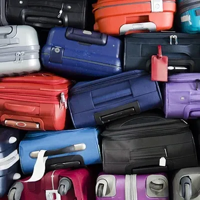 een groot aantal koffers in verschillende kleuren liggen heel dicht op elkaar gestapeld