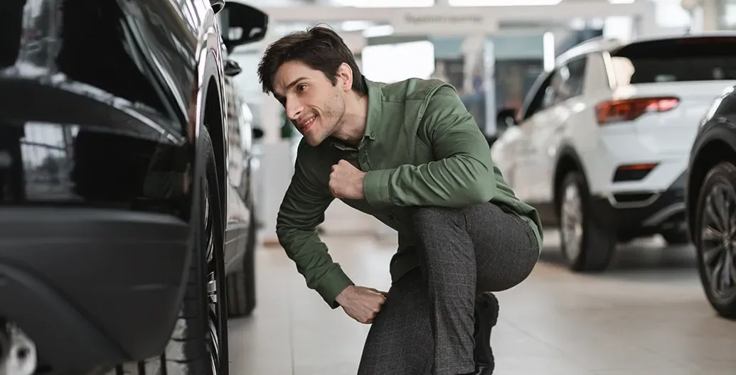 een man bekijkt een auto van dichtbij in een showroom