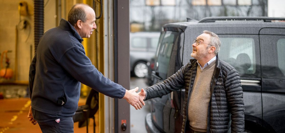 2 mannen schudden handen naast een auto